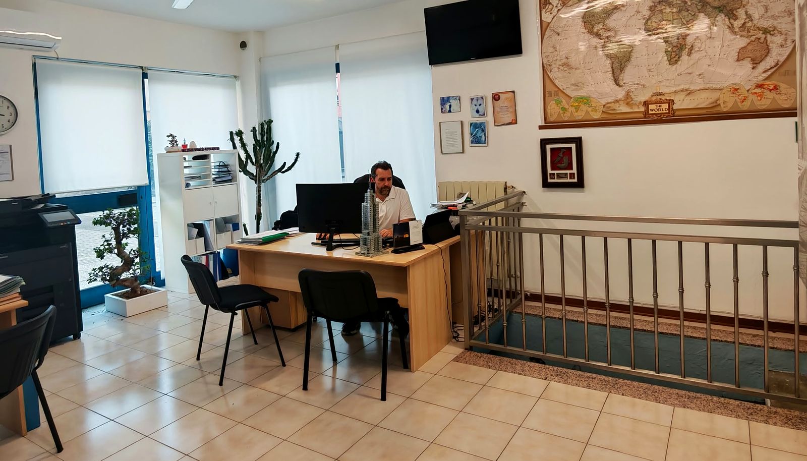 Stefano al banco dell’agenzia Stelema Viaggi a Pero, con la grande mappa del mondo alle spalle