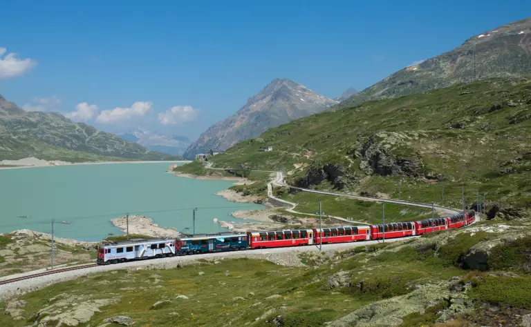 Il Trenino rosso del Bernina lungo il Lago Bianco, tra le montagne